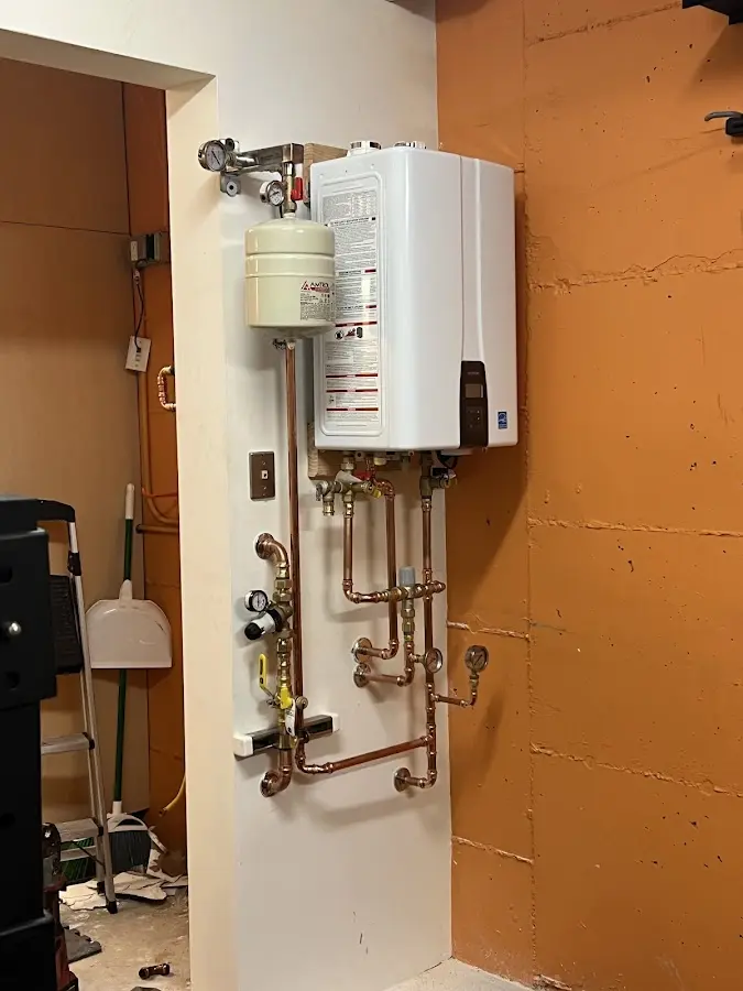 Plumbing technician inspecting water heater connections in Beecher